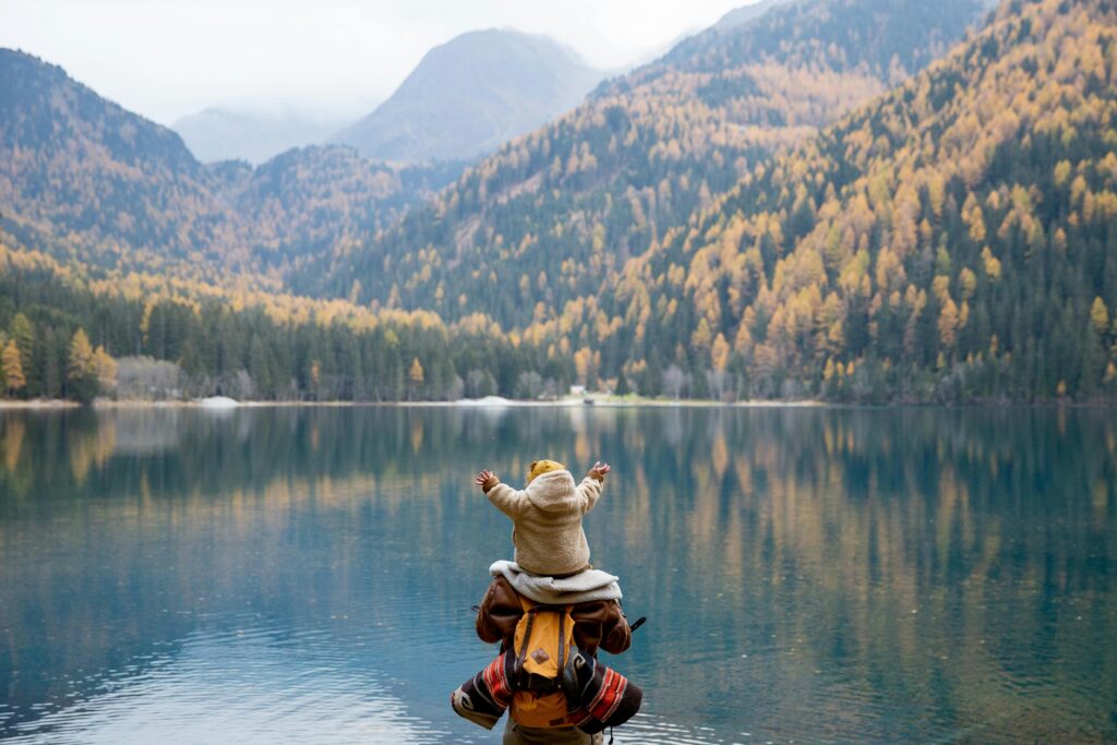 pexels-photo-3933989-3933989-2 A parent and child seated on a lakeside log, enjoying the serene mountain view in autumn.