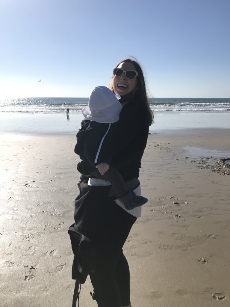 Home Mom holding baby at the beach.